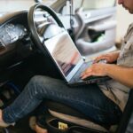 Mechanic using an OBD2 scanner to perform computer diagnostics on a car.