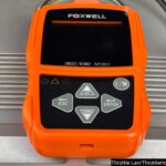 Foxwell NT201 OBD2 Scanner on a car dashboard