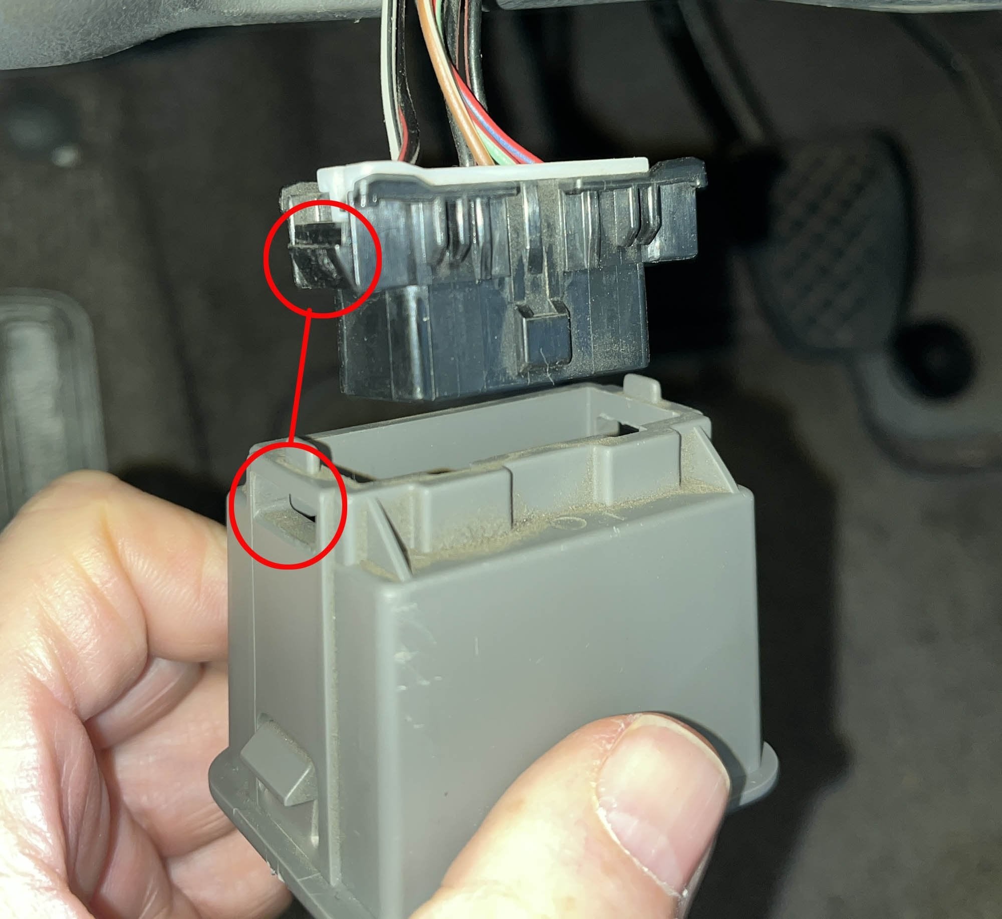 2017 Subaru WRX OBD2 connector separated from its housing, red circles indicating locking tab locations.