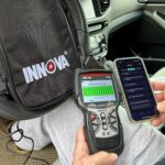 Using an OBD2 scanner to diagnose hybrid car battery issues, as shown with the Innova 5610 model.