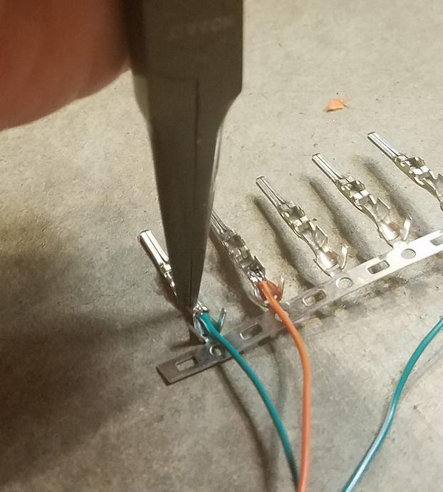 Crimping the connector pin prongs around the wire using pliers