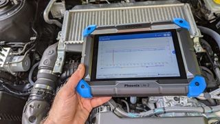 Topdon Phoenix Lite 2 OBD2 scanner positioned over a car engine, emphasizing its advanced features and suitability for professional use